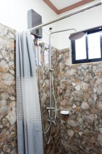 a shower in a bathroom with a stone wall at JUN's INN in Oslob