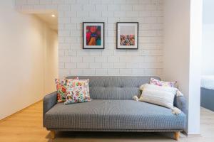 a gray couch in a living room with paintings on the wall at Hermoso Departamento Frente al Aeropuerto in Mexico City