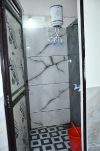 a shower with marble walls and a bucket at KSHIPRA GUEST HOUSE in Ujjain