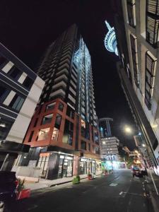 a tall building on a city street at night at Sky tower just next DOOR in Auckland