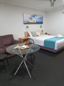 a bedroom with a bed and a table and a couch at Aston Hill Motor Lodge in Port Macquarie