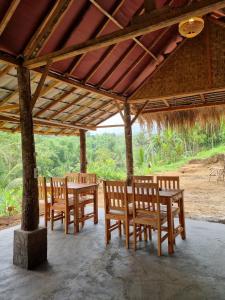 a group of wooden chairs and tables under a pavilion at Tetebatu Jungle Vibes in Tetebatu