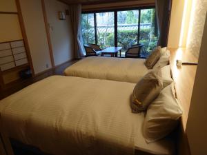 two beds in a hotel room with a window at Kawakamiya Kasuitei in Gero