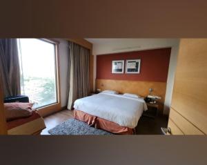 ein Hotelzimmer mit einem Bett und einem großen Fenster in der Unterkunft HOTEL FLAMINGO in Jaipur