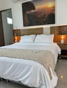 a bedroom with a large white bed with a painting on the wall at Ritacuba House Boutique in Santa Marta