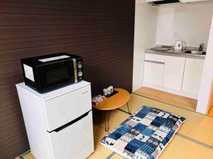 大阪市にある全新上线花跡民宿4号館301，关西机场直达萩之茶屋出站1分钟！难波，心斋桥4分钟车程！の冷蔵庫の上に電子レンジがあるキッチン