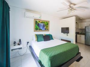 une chambre avec un lit avec une couverture verte dans l'établissement Fiwi-Own Chelsea Manor, Kingston, à Kingston 2 autres photos