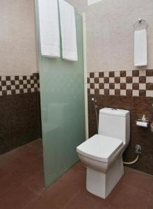 a bathroom with a toilet and a green door at Hotel Terminal View in Bangalore