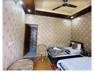 Natraj Heli Resort, Sersi في Phata: غرفة نوم بسريرين واريكة وكرسي