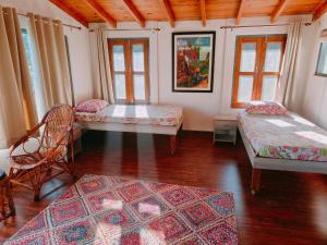 a room with three beds and a chair and windows at Fursat, exclusive solitude! in Rāmgarh