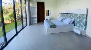 Schlafzimmer mit einem Bett und Glasschiebetüren in der Unterkunft Amelia Misty Hills in Kandy