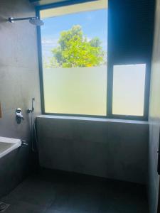 ein Badezimmer mit einem Fenster, einer Badewanne und einem Waschbecken in der Unterkunft Amelia Misty Hills in Kandy