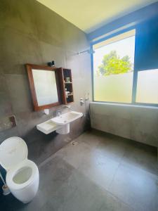 ein Bad mit einem WC, einem Waschbecken und einem Fenster in der Unterkunft Amelia Misty Hills in Kandy