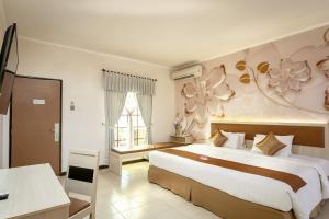 - une chambre avec un grand lit orné d'un mur fleuri dans l'établissement Lombok Garden Hotel, à Mataram