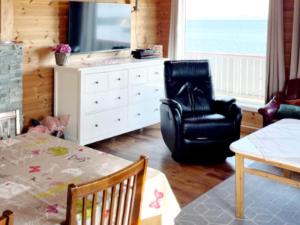 sala de estar con silla negra y cómoda en Three-Bedroom Holiday home in Storfosna, en Sletta