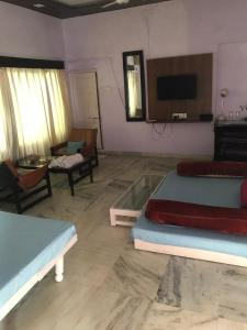 sala de estar con 2 camas y TV en Mewar Inn, en Udaipur
