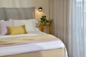 1 cama con almohada amarilla junto a una ventana en Mirivili Rooms & Suites, en Atenas