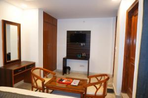 um quarto com uma mesa e cadeiras e um espelho em Ganeshwaram Hotel Sector-45 Noida em Noida