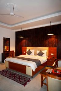 - une chambre avec un grand lit et une tête de lit en bois dans l'établissement Ganeshwaram Hotel Sector-45 Noida, à Noida
