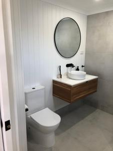 a bathroom with a toilet and a sink and a mirror at The White Room in Yeppoon