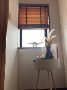 un vaso seduto su un tavolo di fronte a una finestra di かつやま民泊きねん a Katsuyama