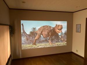 Un dipinto di un dinosauro su un muro di かつやま民泊きねん a Katsuyama