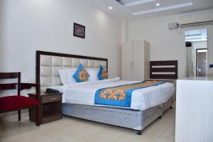 een slaapkamer met een groot bed en een rode stoel bij Hotel Nirvana Suites in New Delhi