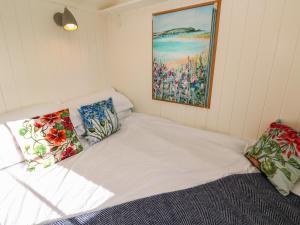 a bed in a room with a painting on the wall at Lower Trewern Shepherds Hut in Penzance