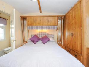 um quarto com uma grande cama branca com almofadas roxas em Little Malory em Launceston