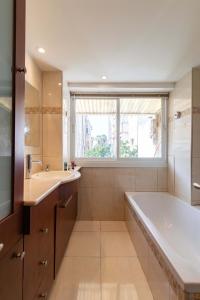 een badkamer met een bad, een wastafel en een raam bij Hilton Beach 2BR in Tel Aviv