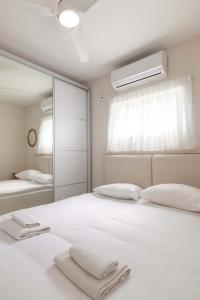 a bedroom with a large white bed with a mirror at Hilton Beach 2BR in Tel Aviv