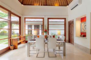 Villa Dorado - Steps from Jimbaran Beach في جيمباران: غرفة طعام مع طاولة وكراسي