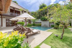 uma imagem de um quintal com uma piscina e um guarda-sol em Villa Dorado - Steps from Jimbaran Beach em Jimbaran