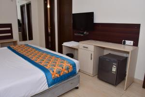 a bedroom with a bed and a desk with a television at Hotel Nirvana Suites in New Delhi