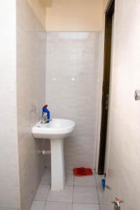 a white bathroom with a sink and a shower at Beach Box Dimash Apartments in Mombasa