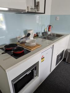 a kitchen with a counter with a stove and a sink at PROSERPINE MOTOR LODGE in Proserpine