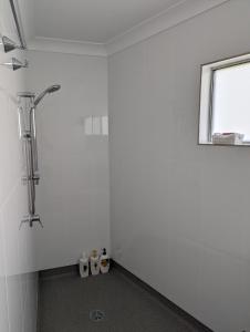 baño blanco con ducha y ventana en PROSERPINE MOTOR LODGE en Proserpine