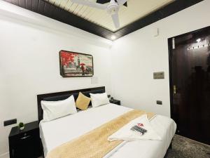 Un dormitorio con una cama blanca y una foto en la pared en Roomshala 166 Hotel You Own - Vikas Puri en Nueva Delhi