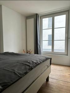 a bed in a room with a large window at Charming Bohemian central app in Antwerp