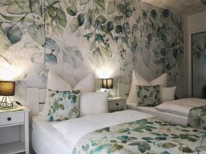 2 łóżka w sypialni z tapetą w kwiaty w obiekcie Anna Panzió w mieście Herend