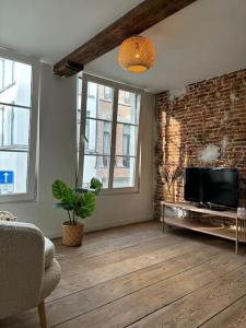a living room with a television and a brick wall at Charming Bohemian central app in Antwerp