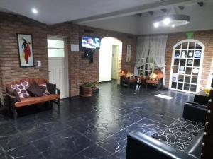 a living room with couches and a tv on a brick wall at Hotel Posada Sol in Villa Carlos Paz