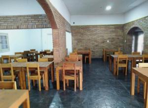 a restaurant with wooden tables and chairs and a brick wall at Hotel Posada Sol in Villa Carlos Paz