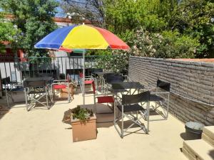 a colorful umbrella on a patio with chairs and tables at Hotel Posada Sol in Villa Carlos Paz