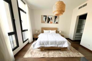 a white bedroom with a bed and a rug at BambooStays Cozy 2BR at Cairo Festival in Cairo