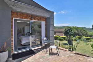 a patio with a bed and a table and chairs at Sleep Haven Self-Catering Accommodation - Nelspruit in Nelspruit