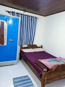 a bedroom with a bed and a blue door at Brindavan cottage in Madikeri