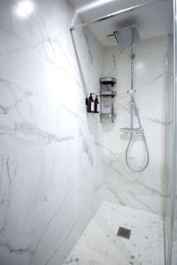a bathroom with a shower with white marble walls at SAULSTICE, Appartement cosmique hyper centre in Auxerre
