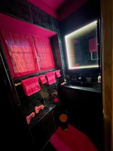 Love Room du Moulin Rose في ترانس-إن-بروفنس: حمام مظلم مع مناشف وردية ومغسلة