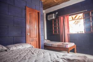 a bedroom with a blue wall with a bed and a window at Hostel El Gran Azul Olon in Olón +27 photos